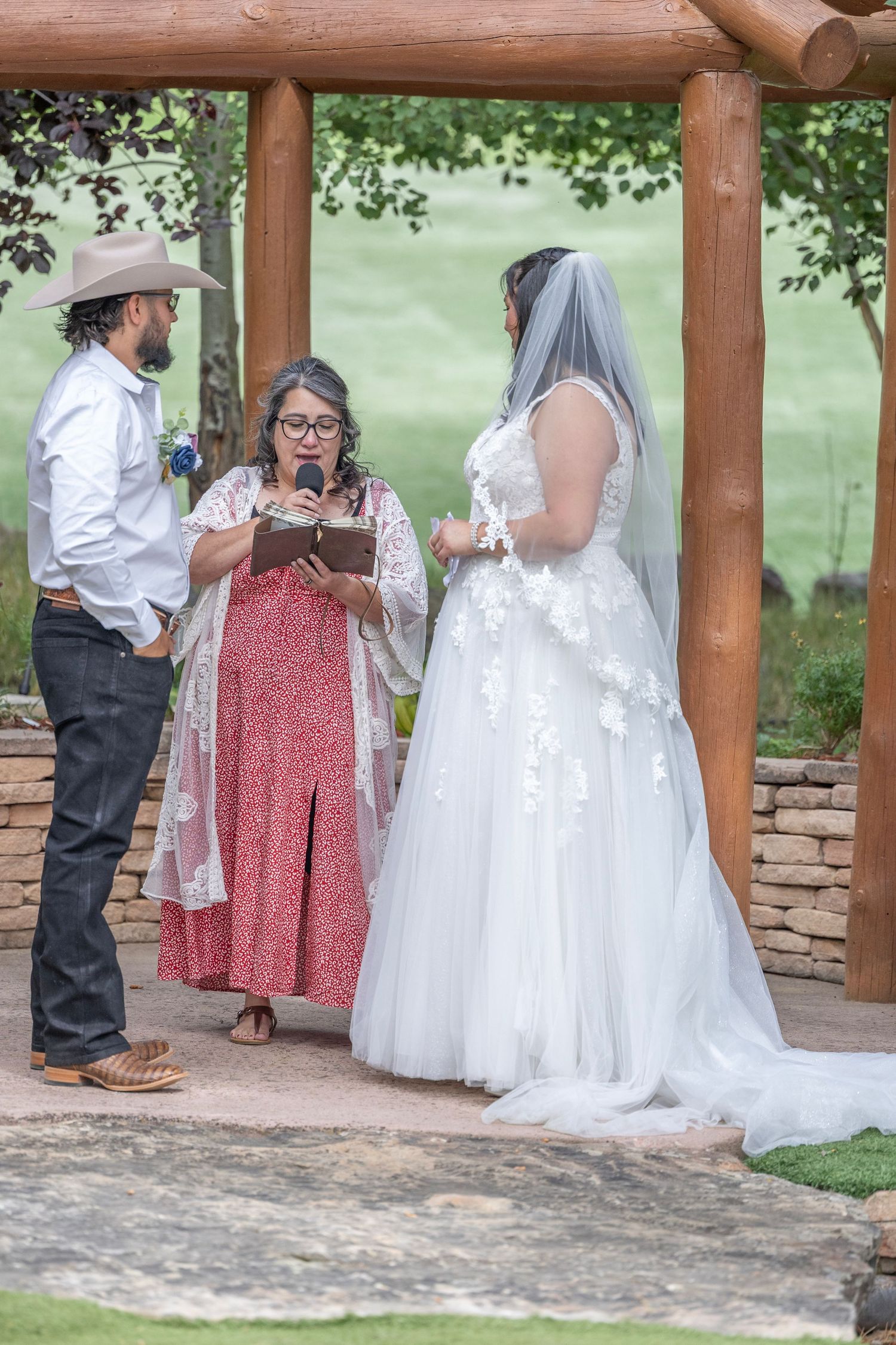 A series of candid moments at an outdoor wedding ceremony under a wooden pavilion with stone walls and green scenery.