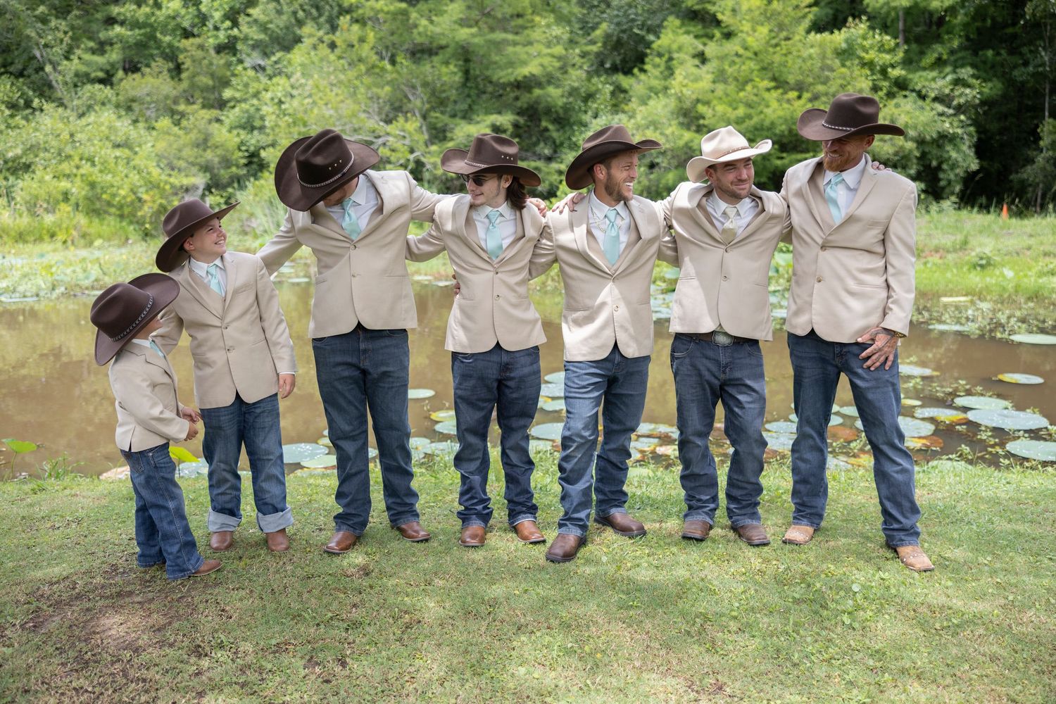 Group of children in matching khaki uniforms and jeans lined up outdoors for a photo.