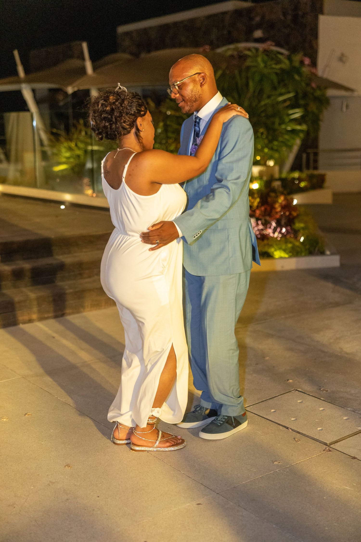 A couple dances together at dusk on an outdoor patio in a romantic moment.