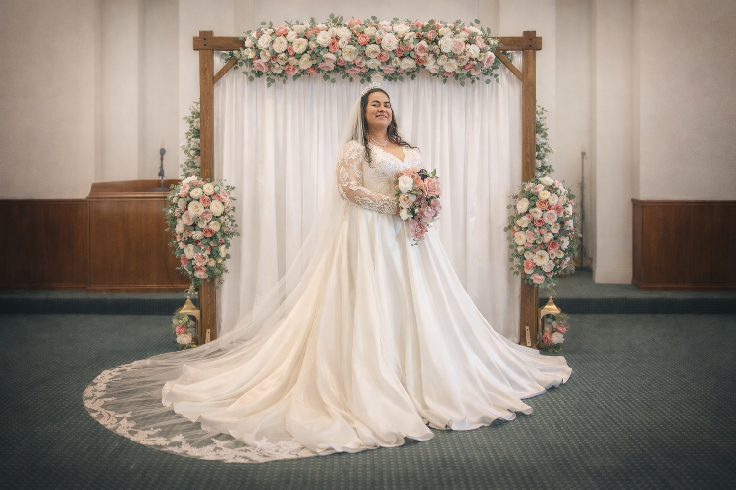 Bride in elegant white ball gown with long train stands before floral arch with pink roses in decorated ceremony hall.