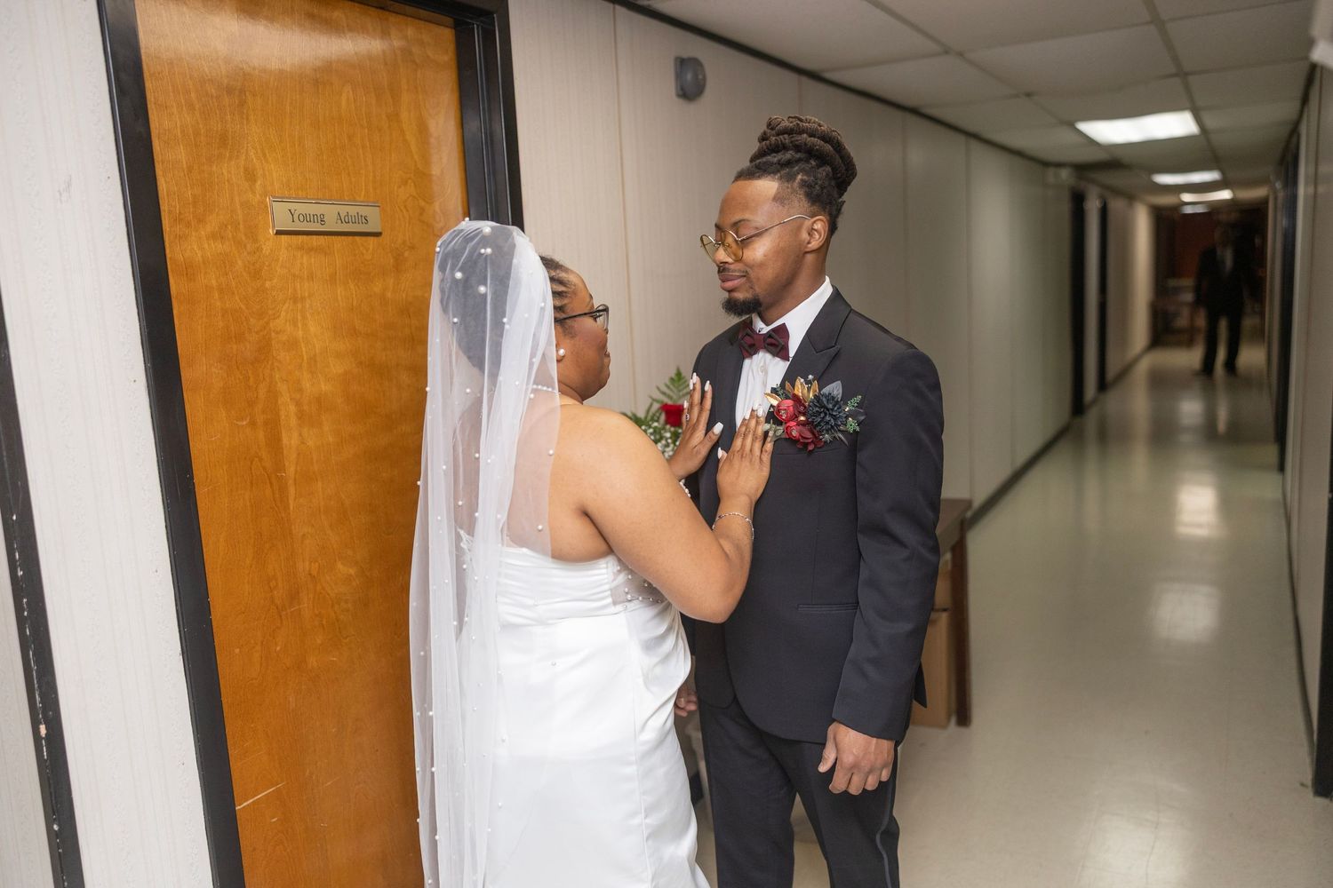 A bride and groom share a joyful moment in a hallway during their wedding celebration.