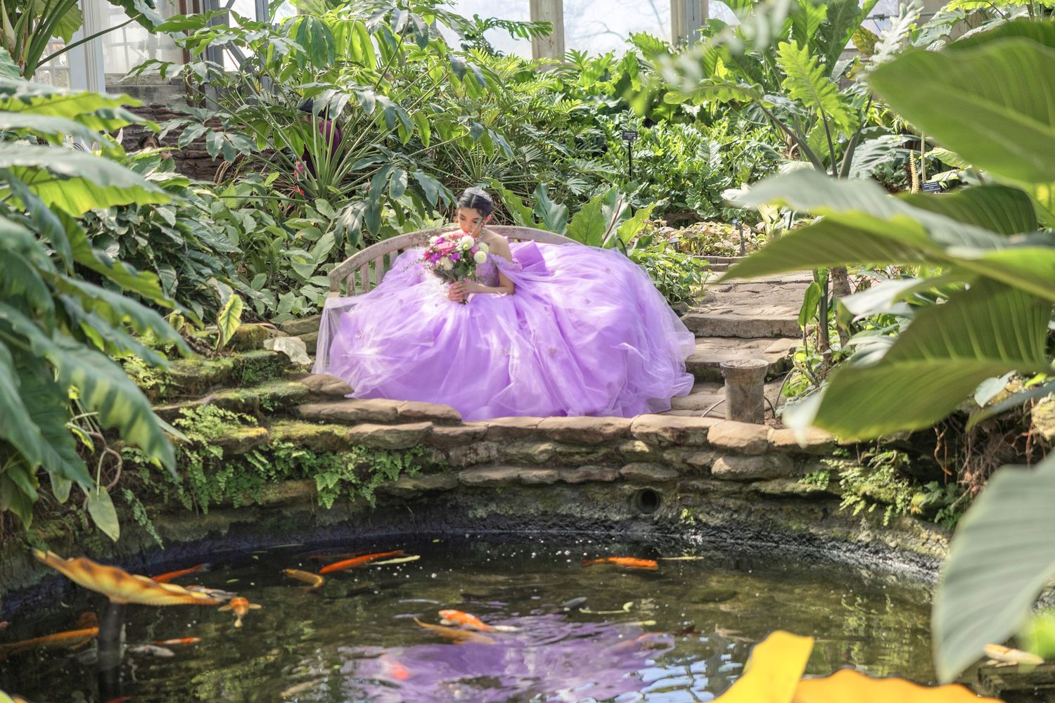A serene koi pond surrounded by lush tropical plants and banana leaves creates a peaceful garden atmosphere.