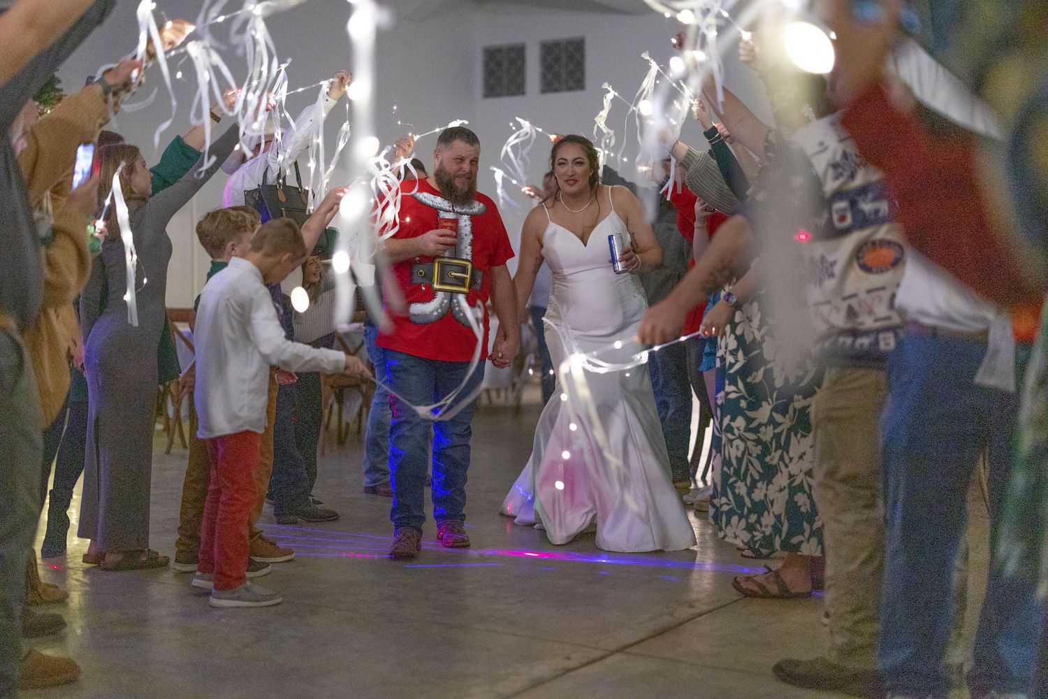 Guests celebrate at a wedding reception with sparklers and dancing in a festively decorated indoor venue.