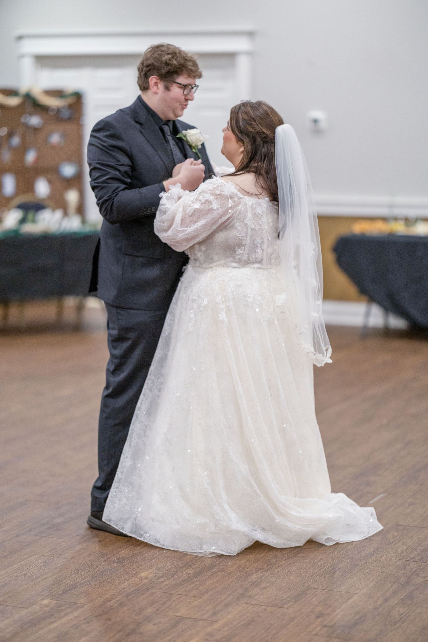 Newlyweds share their first dance together on a wooden dance floor at their wedding reception.