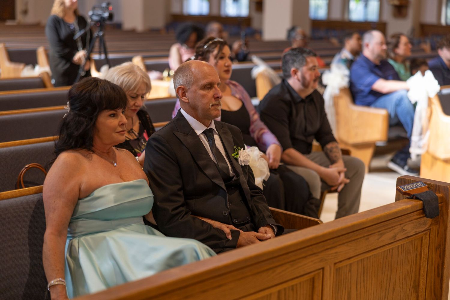 Wedding guests seated in wooden church pews during a traditional ceremony.