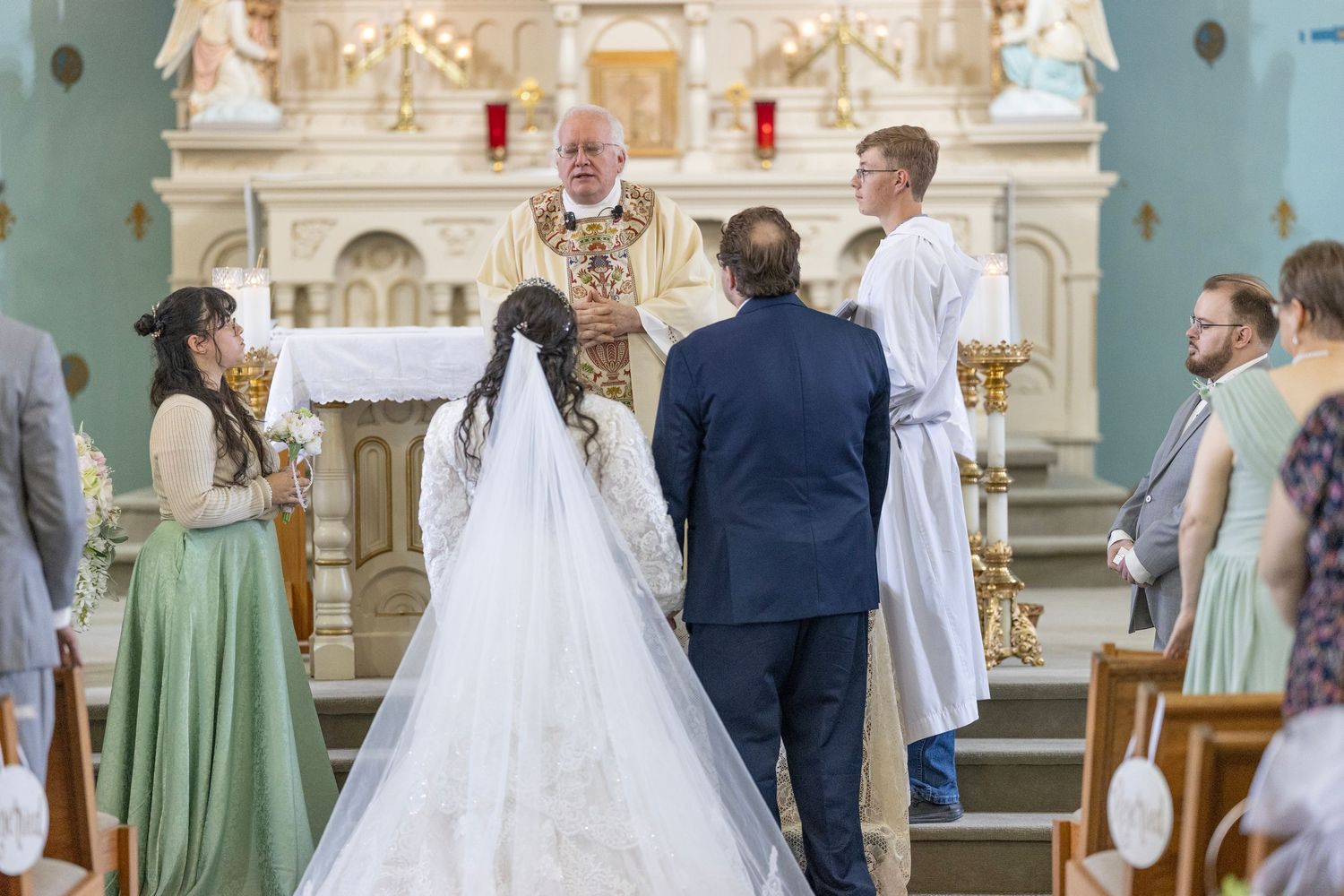 Wedding ceremony taking place in an elegant blue and white church with ornate decorations and stained glass windows.