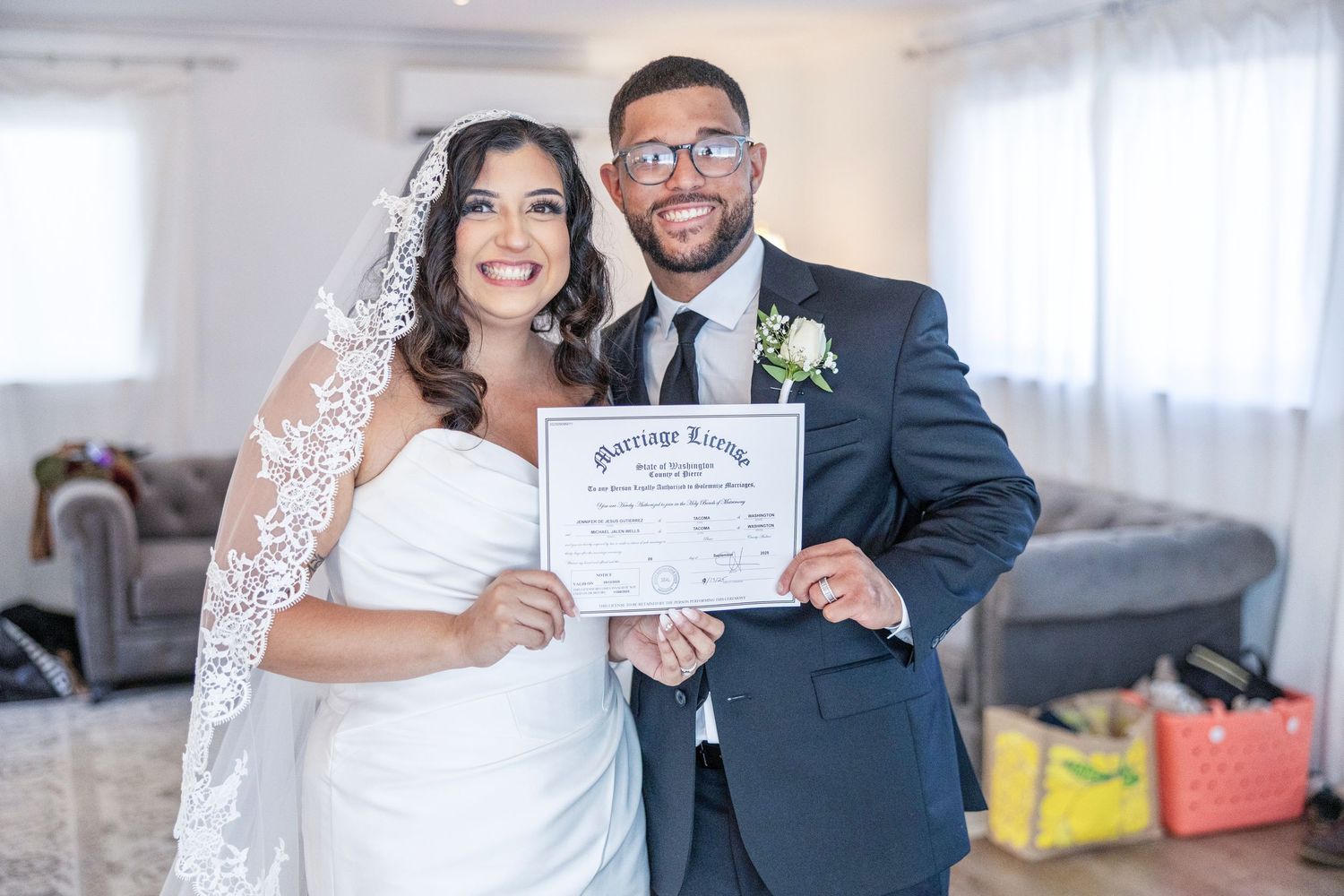 A joyful couple holds up their marriage certificate during an intimate indoor wedding ceremony.