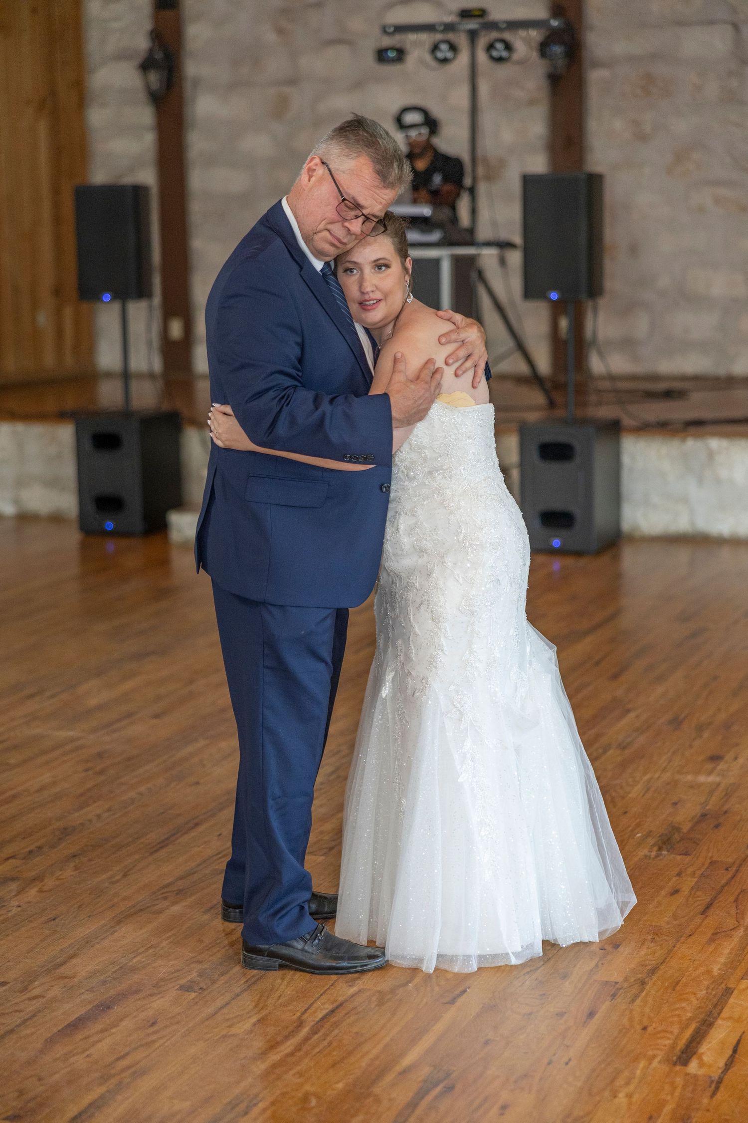A series of wedding photos showing a couple in navy suit and white dress sharing an intimate dance moment on wooden floors.
