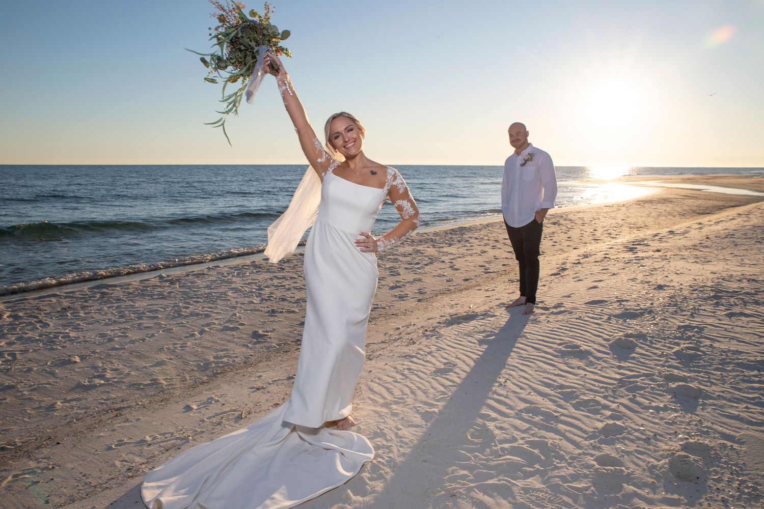 Couple walking hand in hand along a scenic beach at sunset while waves gently roll onto the shore.