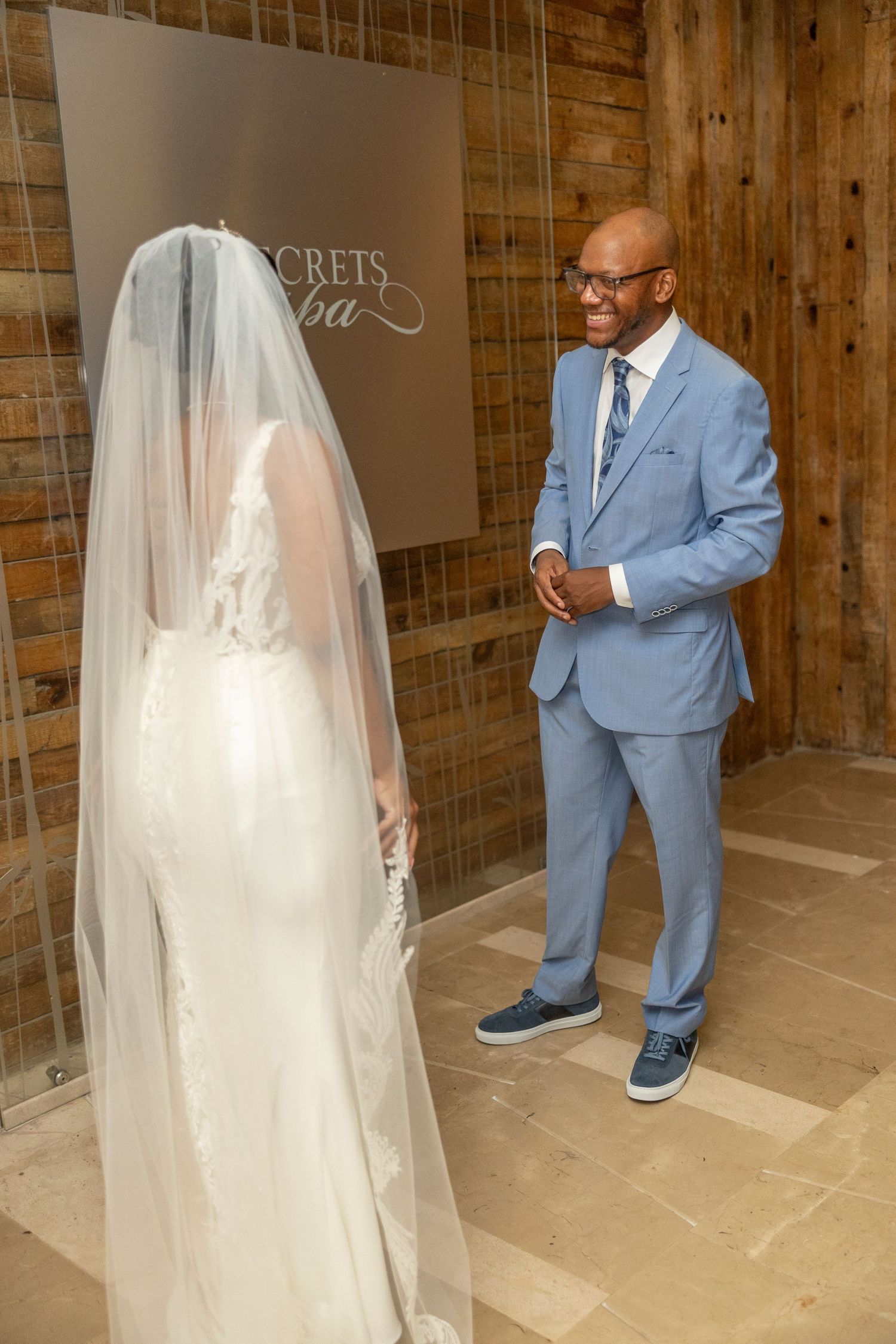 A heartwarming first look moment between a bride in a flowing white gown and groom in a light blue suit.