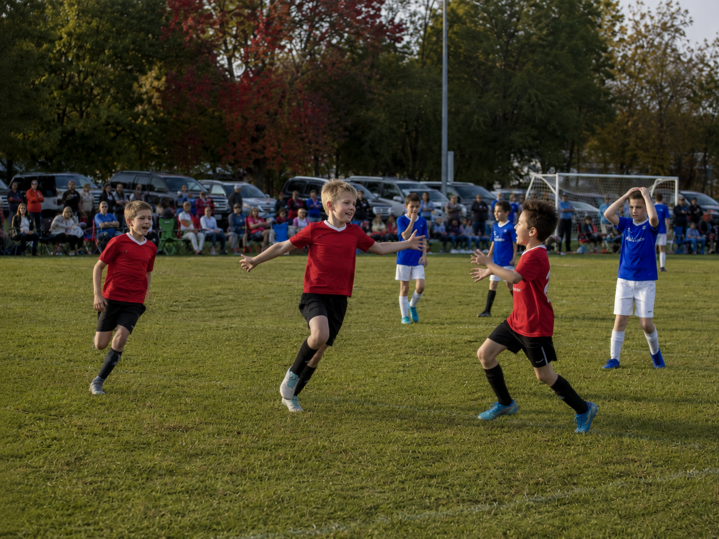 Young soccer players in red uniforms celebrate a goal during an autumn evening youth soccer match.