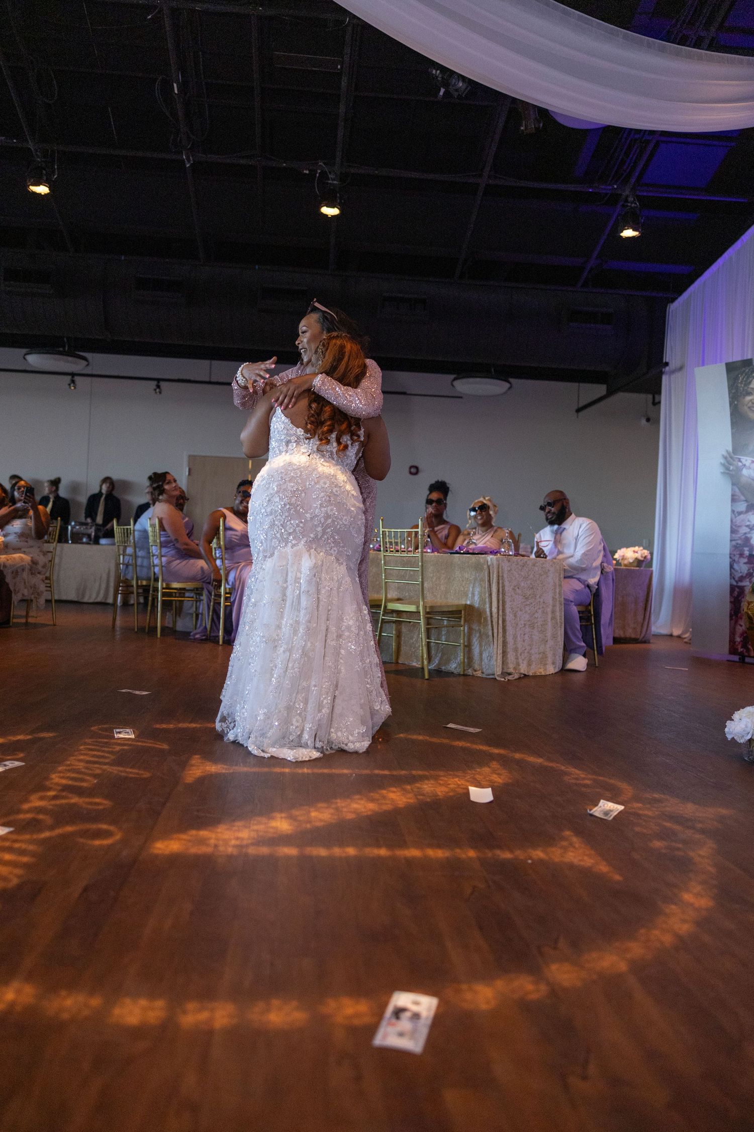 Bride in white lace mermaid gown shares first dance embrace at elegant wedding reception venue.