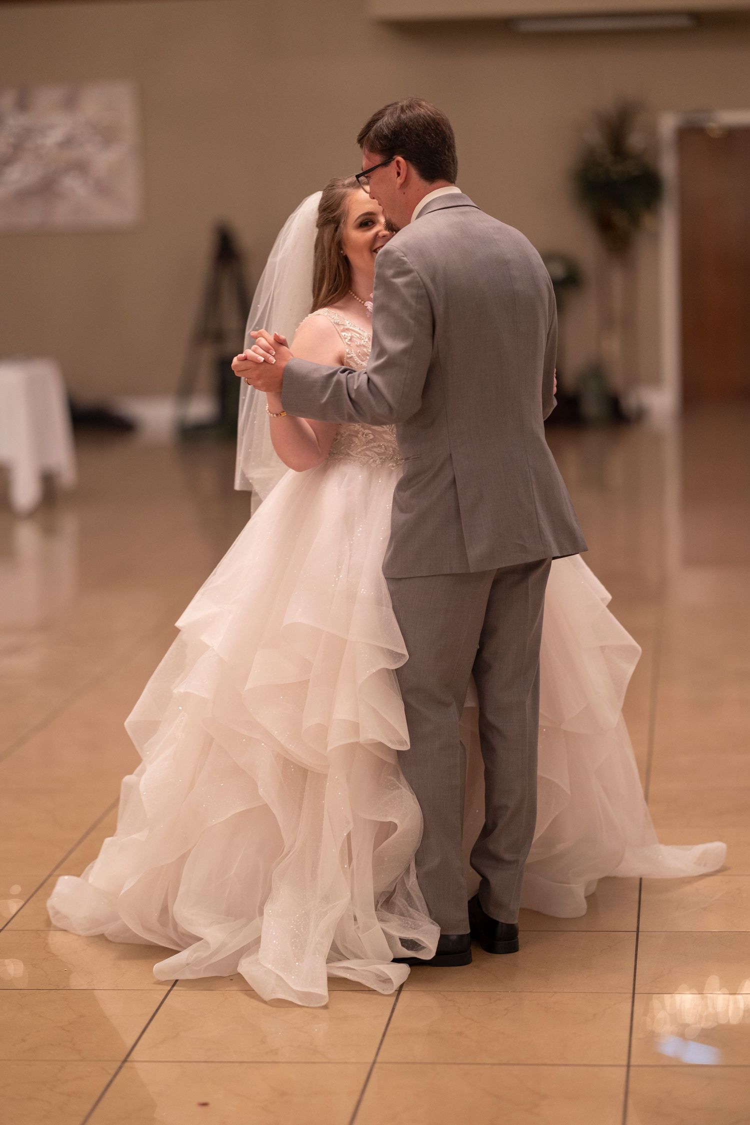 First dance moment at wedding reception on wooden dance floor.
