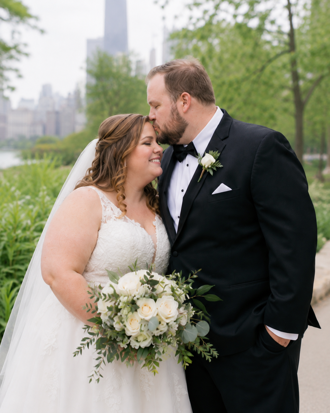 A bride and groom share a romantic moment outdoors in Chicago, with the bride holding a white and greenery bouquet.