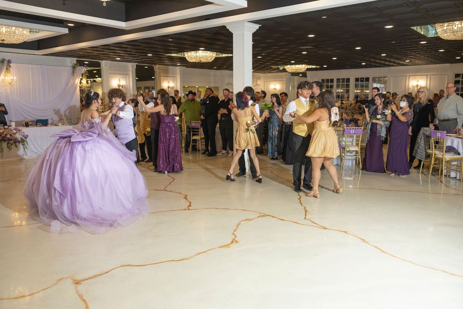 Panoramic view of a large ballroom filled with people dancing and celebrating at a formal event.
