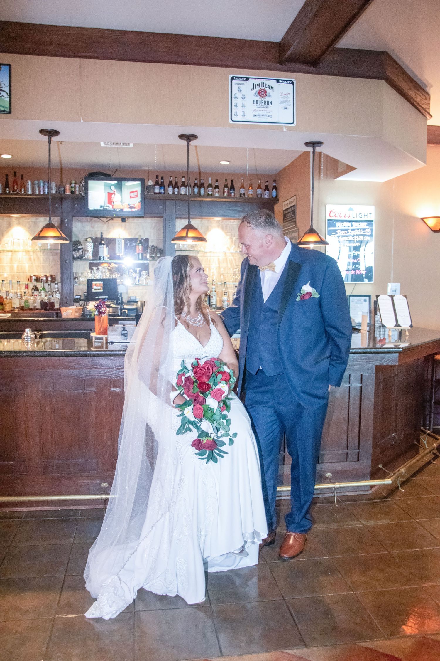 Wedding couple shares a romantic first dance together on a polished wooden floor in a rustic reception venue.