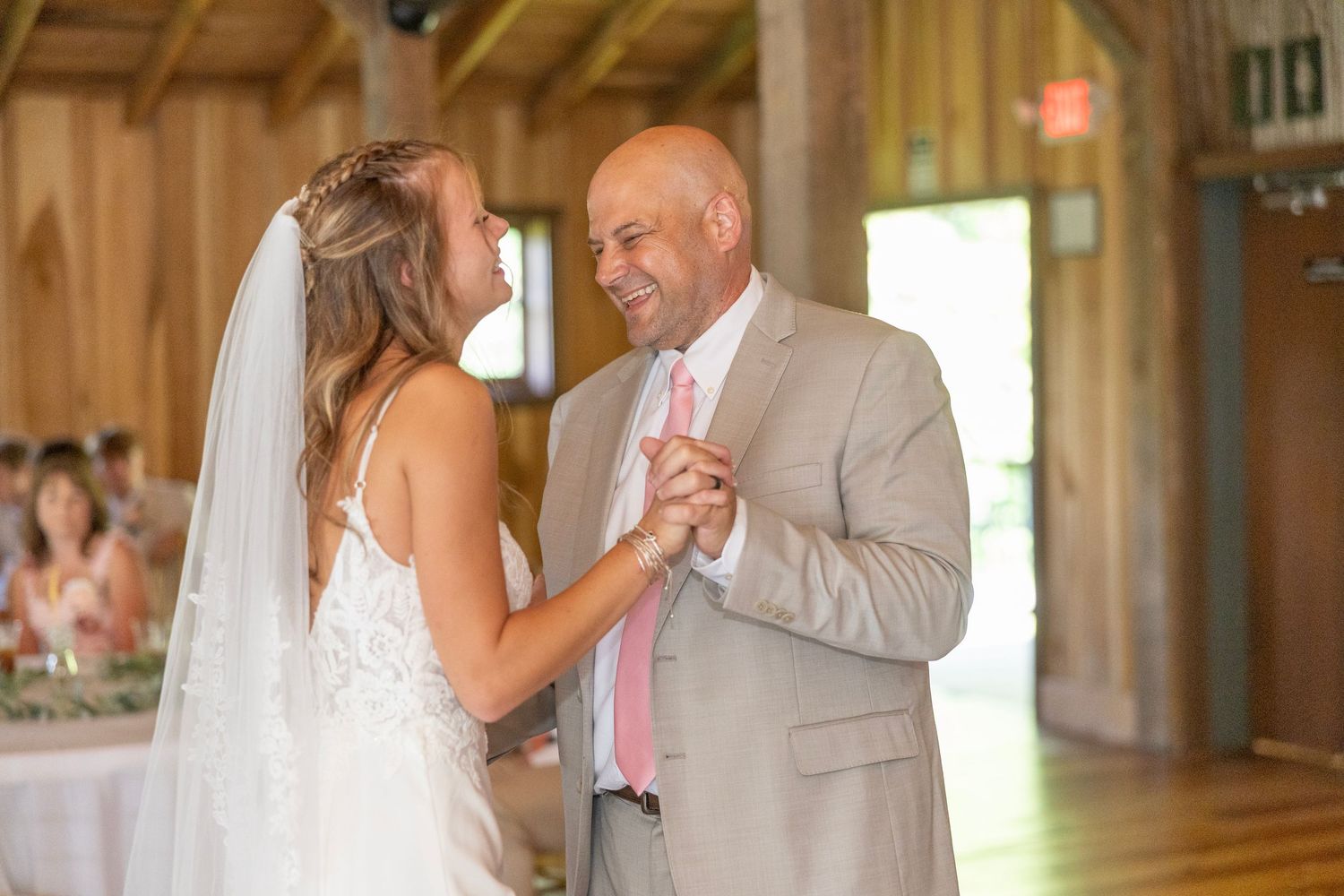 A tender father-daughter dance moment at a rustic barn wedding reception.