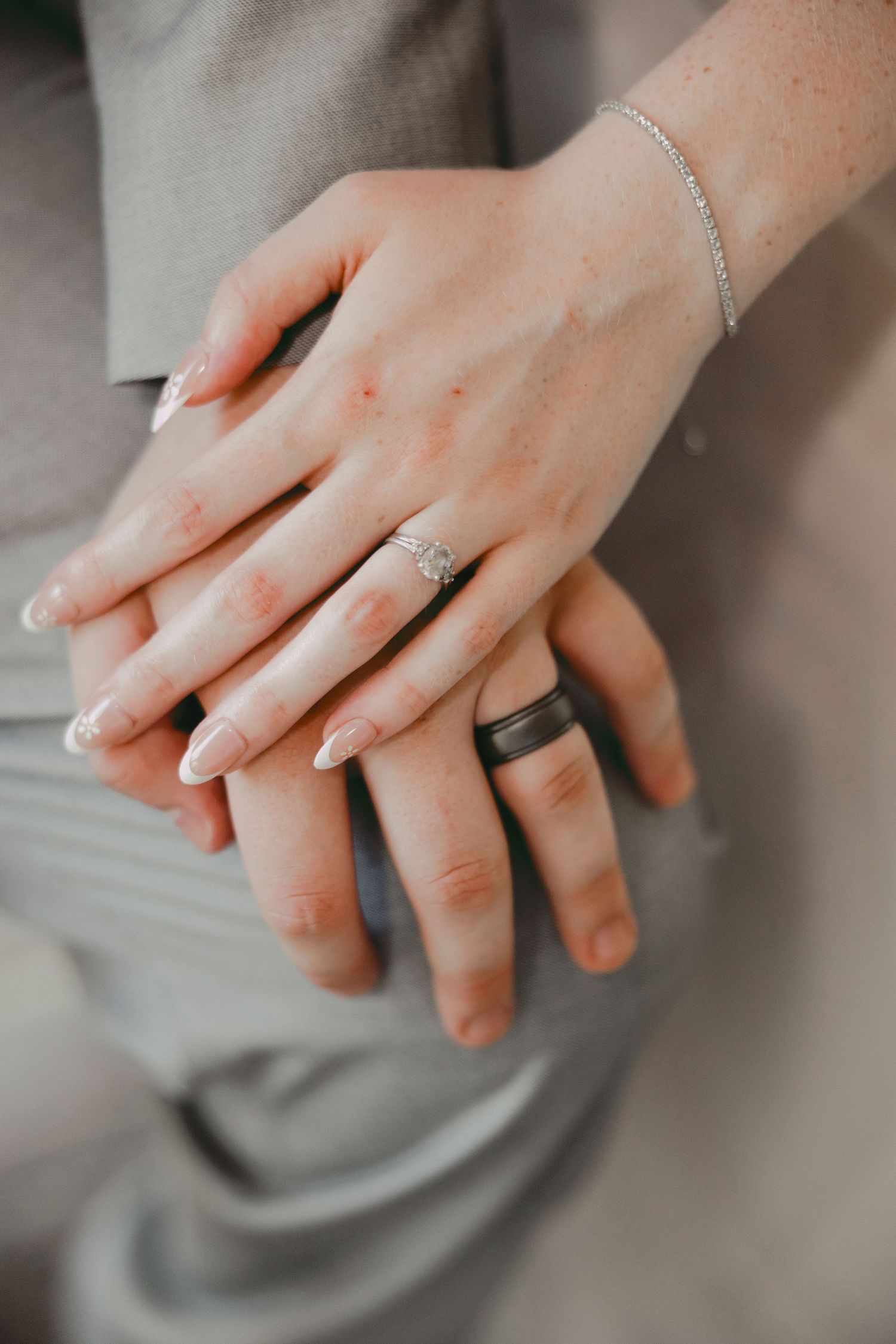 Close-up shots of hands wearing delicate diamond wedding rings and bracelets against a soft gray background.