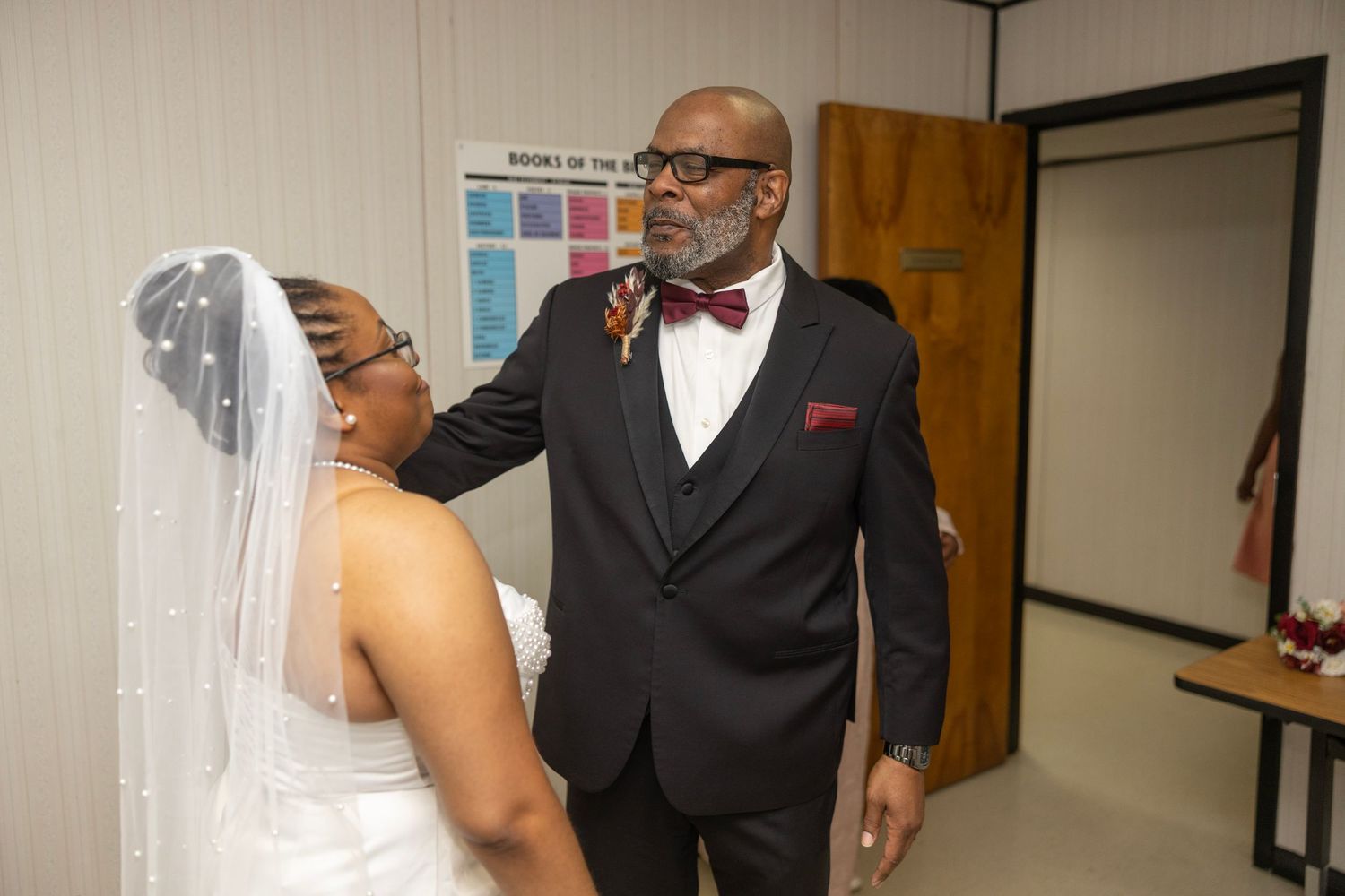 A couple in formal wedding attire shares a joyful moment in an indoor setting.