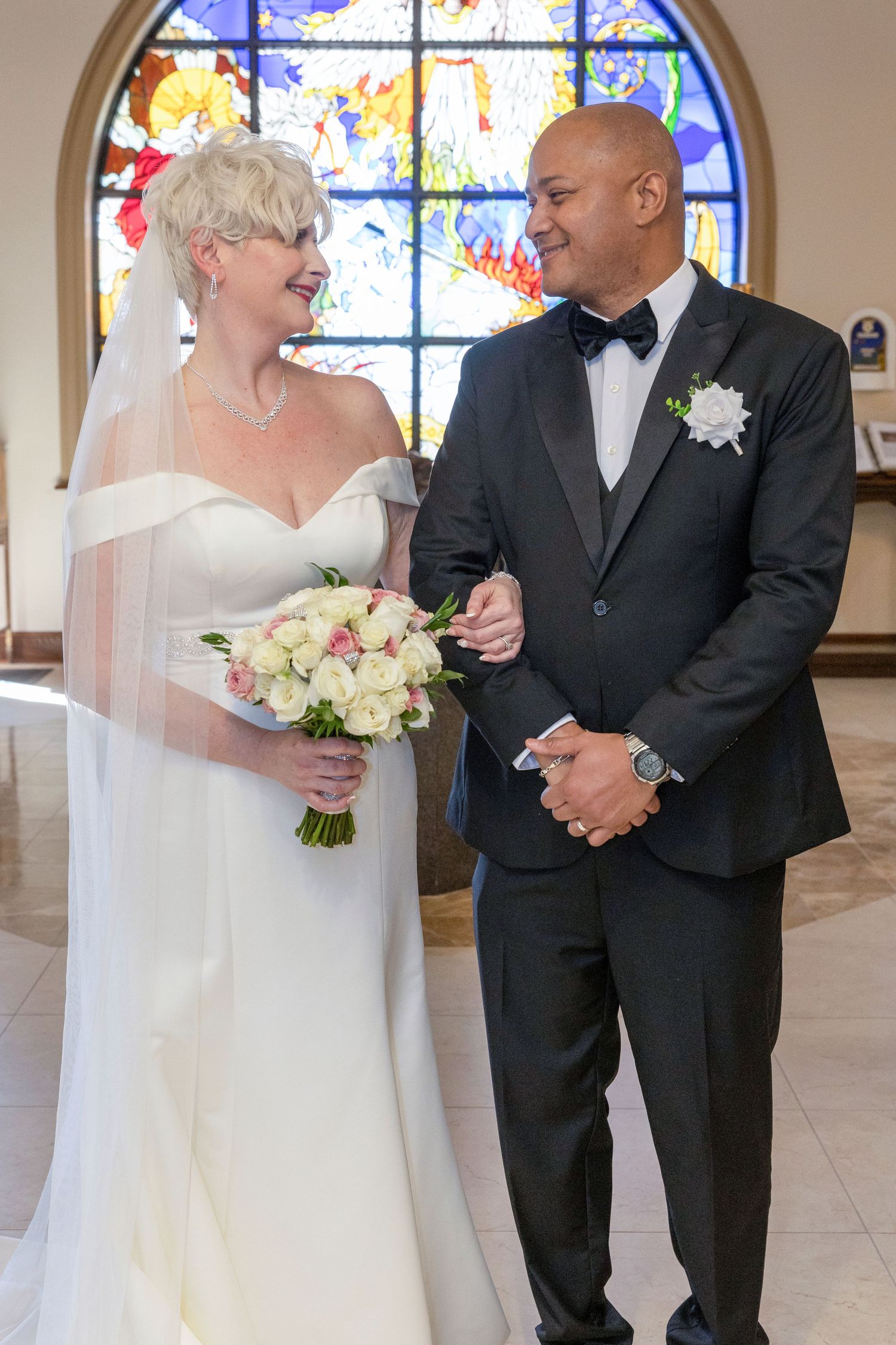 A joyful wedding moment captured in a church with stained glass windows and white columns.