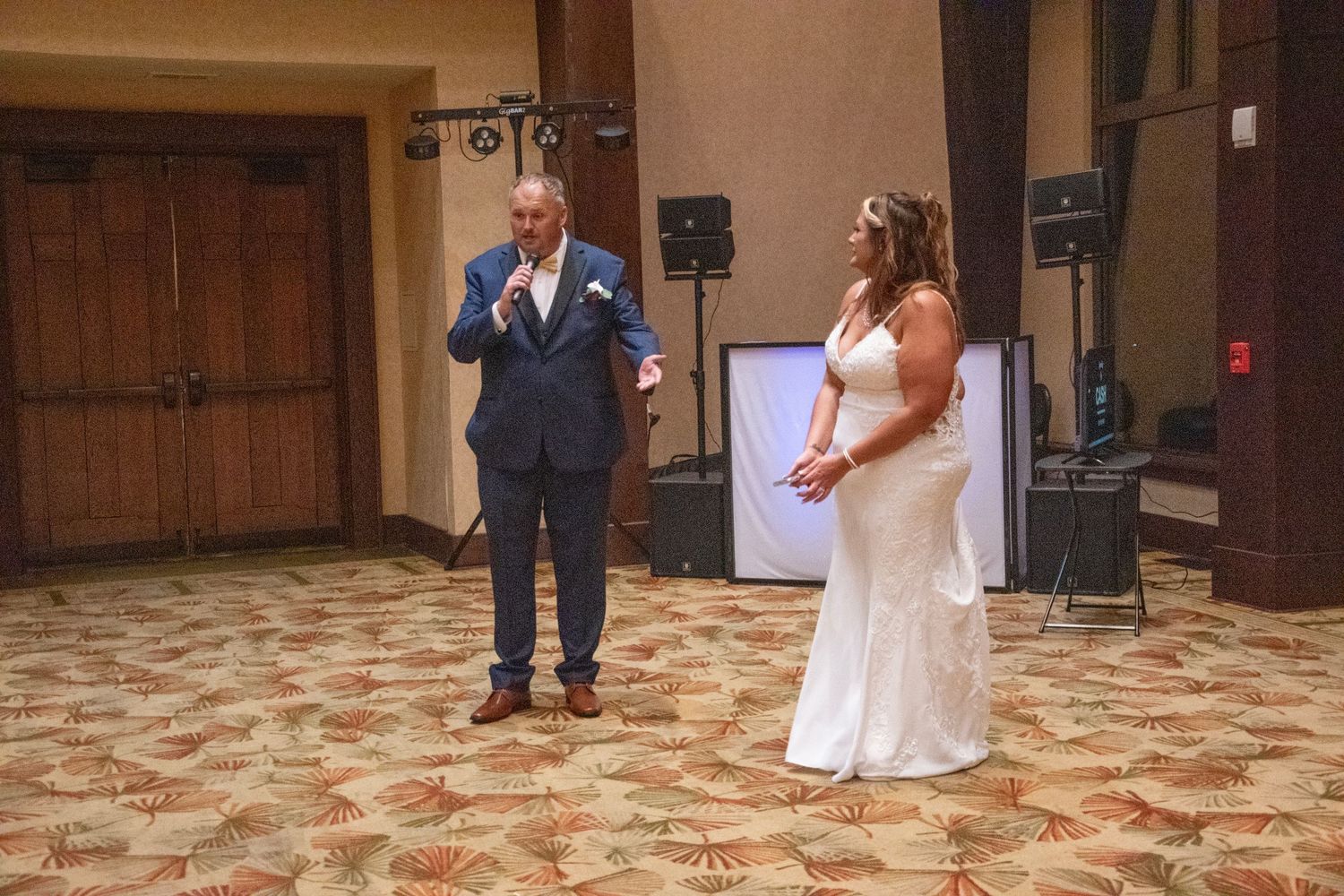 Two people share a moment on a dance floor with patterned tile in an elegant reception venue.