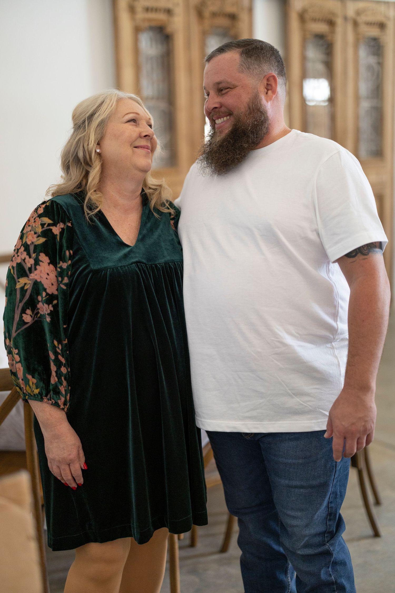 A couple shares a candid moment together in an elegant indoor setting with emerald green velvet clothing.