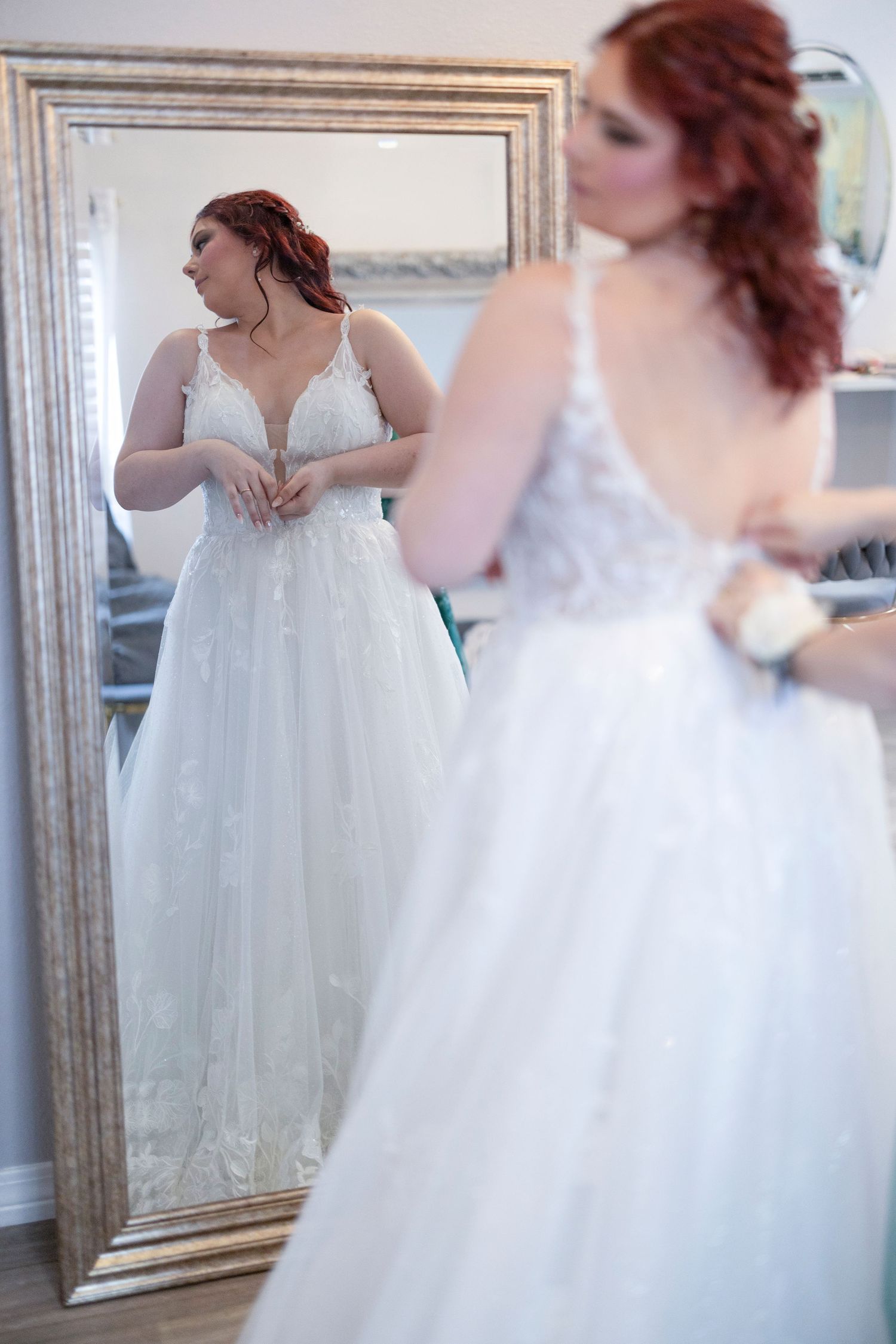 A bride in a flowing white wedding gown spins gracefully in front of an ornate mirror during her wedding preparations.