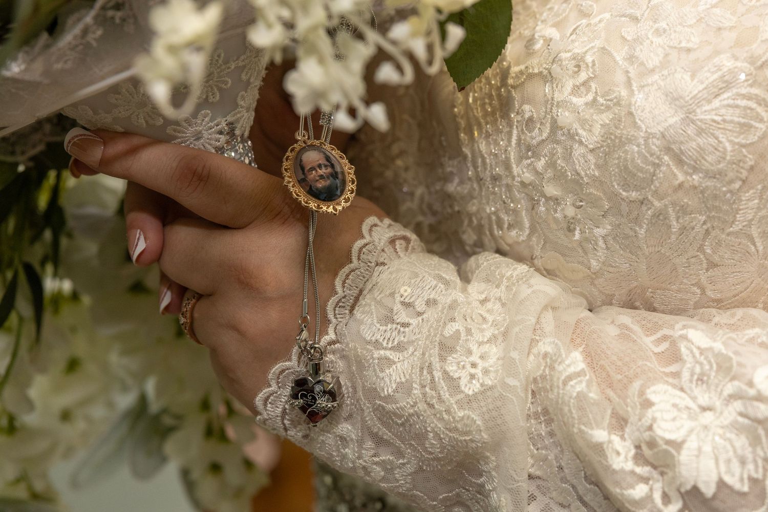 Close-up detail of an ornate lace wedding dress with delicate floral embroidery patterns.