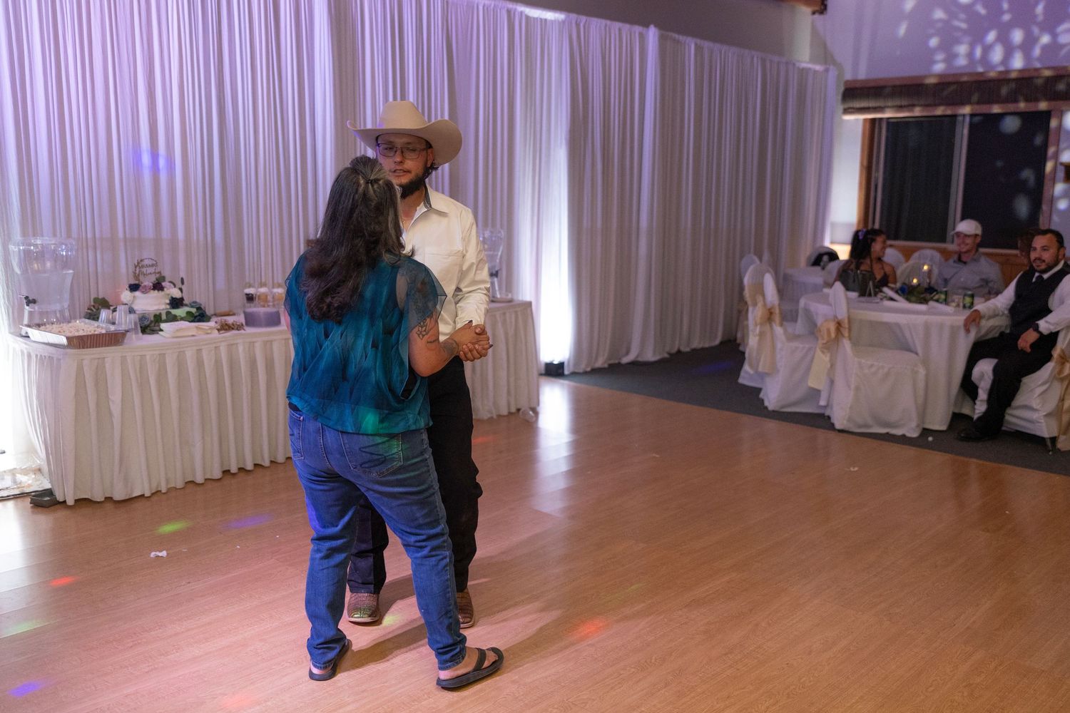 Couples dancing together on a white-curtained dance floor at an elegant indoor event space.
