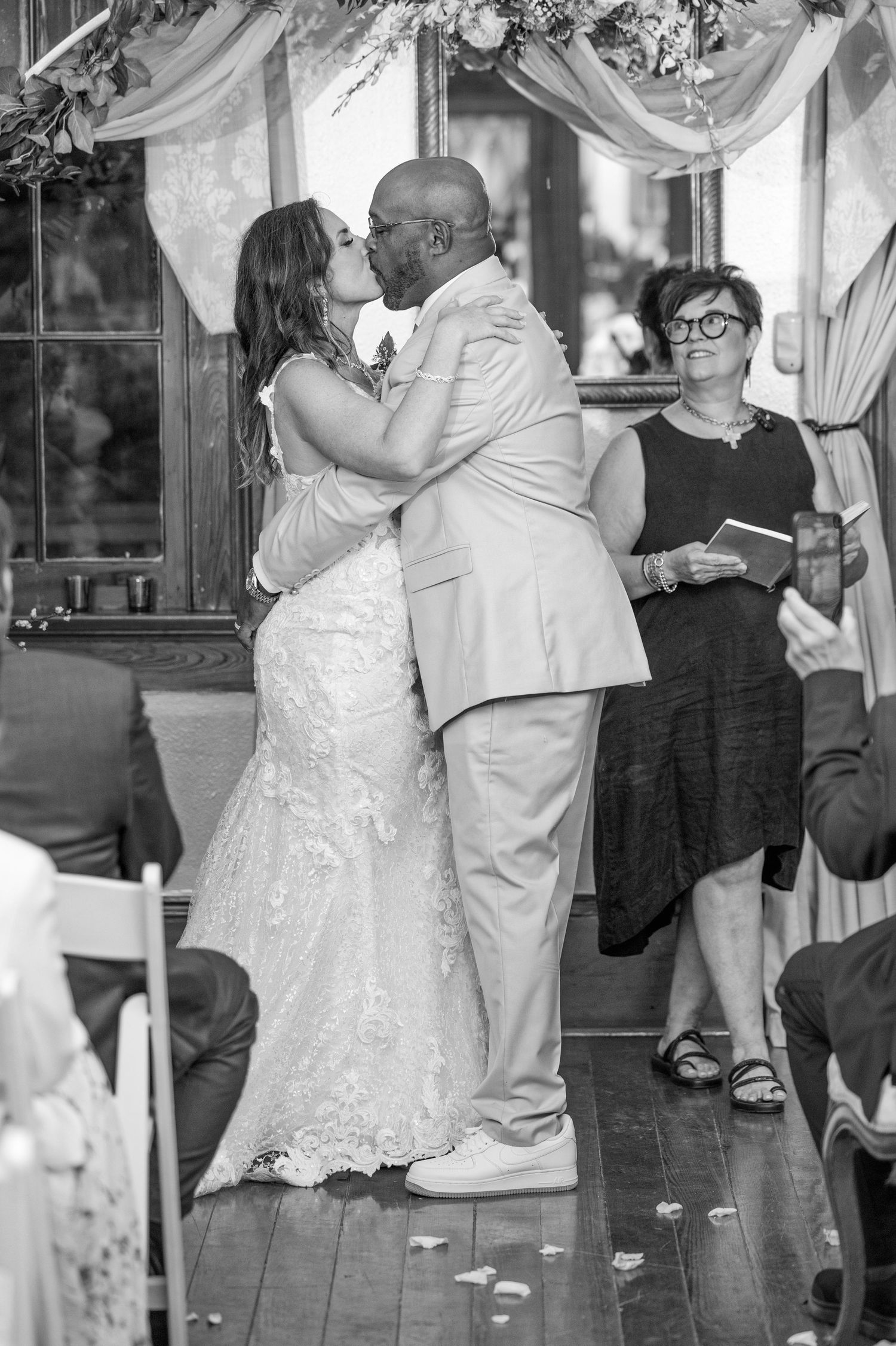 A bride and groom share a romantic dance together at their wedding reception while guests look on.