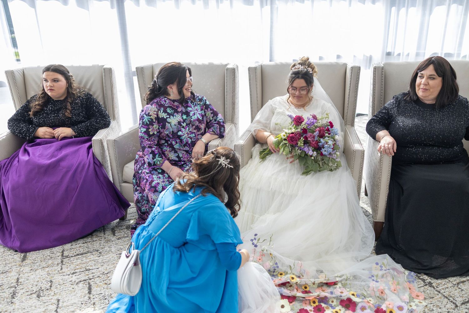 A group of people participate in a floral arranging workshop with colorful flowers and vases on a long table.