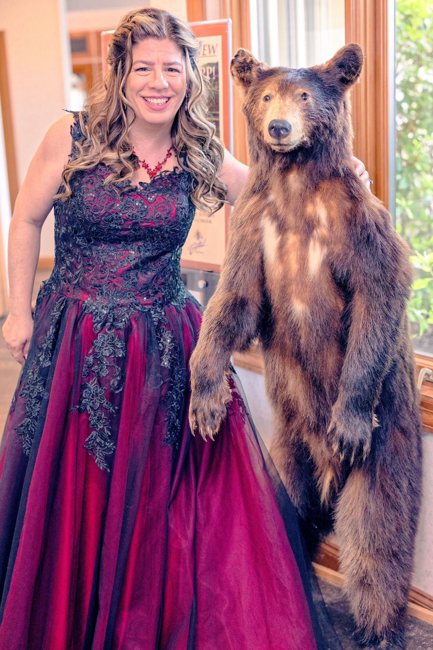 A person in a burgundy formal dress poses with a large brown dog in a series of four similar photos.