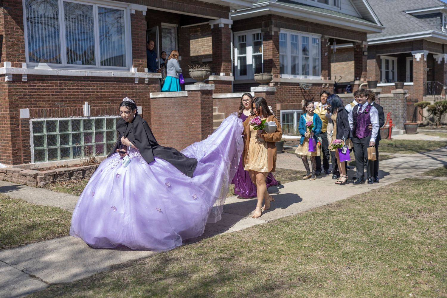 Students hold a large purple parachute during an outdoor activity at a brick school building.