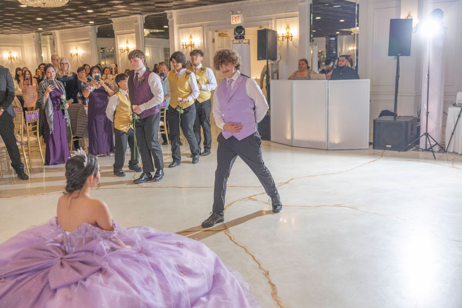 Dancers in purple and formal attire perform during a social ballroom dance event in an elegant indoor venue.