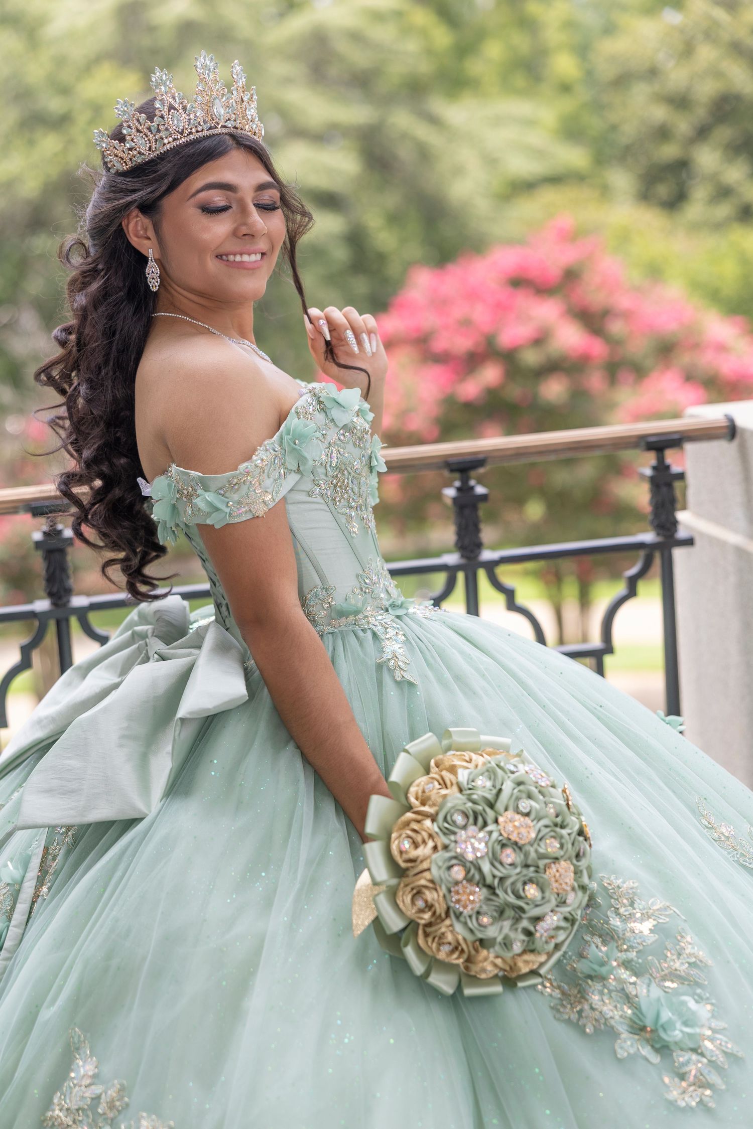A quinceañera celebration featuring a mint green ball gown with floral details and a matching bouquet in an outdoor setting.
