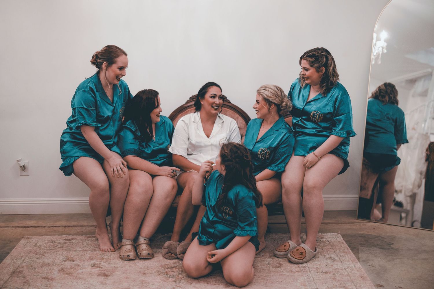 A group wearing matching teal uniforms sits together on a floor in a casual indoor setting.