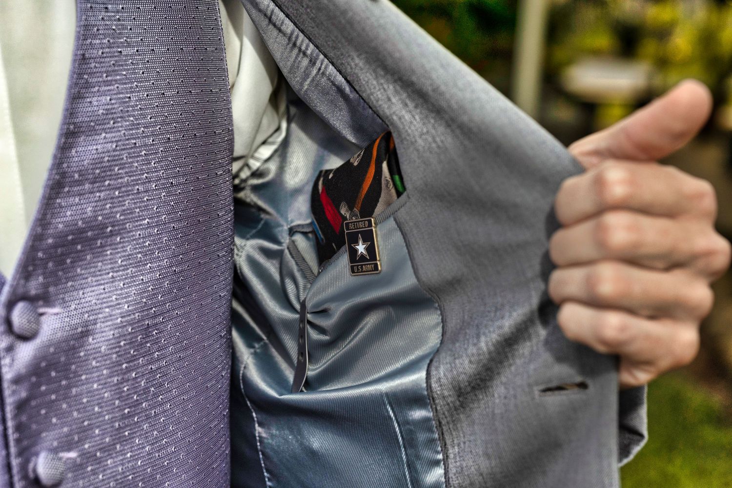Close-up detail shot of a purple and grey suit pocket with hidden accessories.