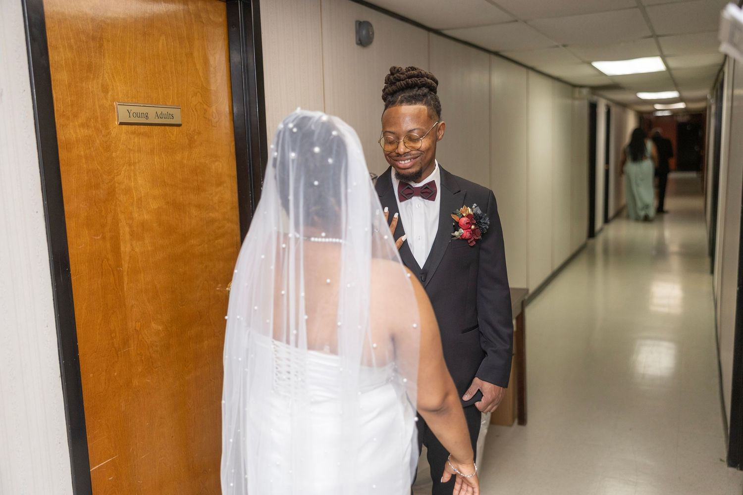 Healthcare worker in scrubs and face mask walks down a bright hospital hallway.