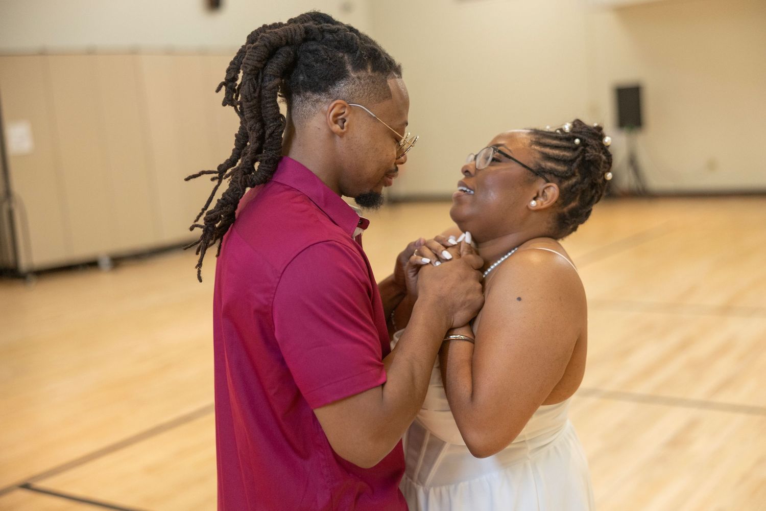 Two dancers in pink and black outfits practice their performance routine in a dance studio.