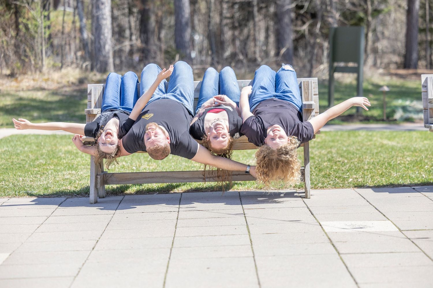A series of people lying on a stone surface outdoors in matching blue outfits arranged in a line formation.