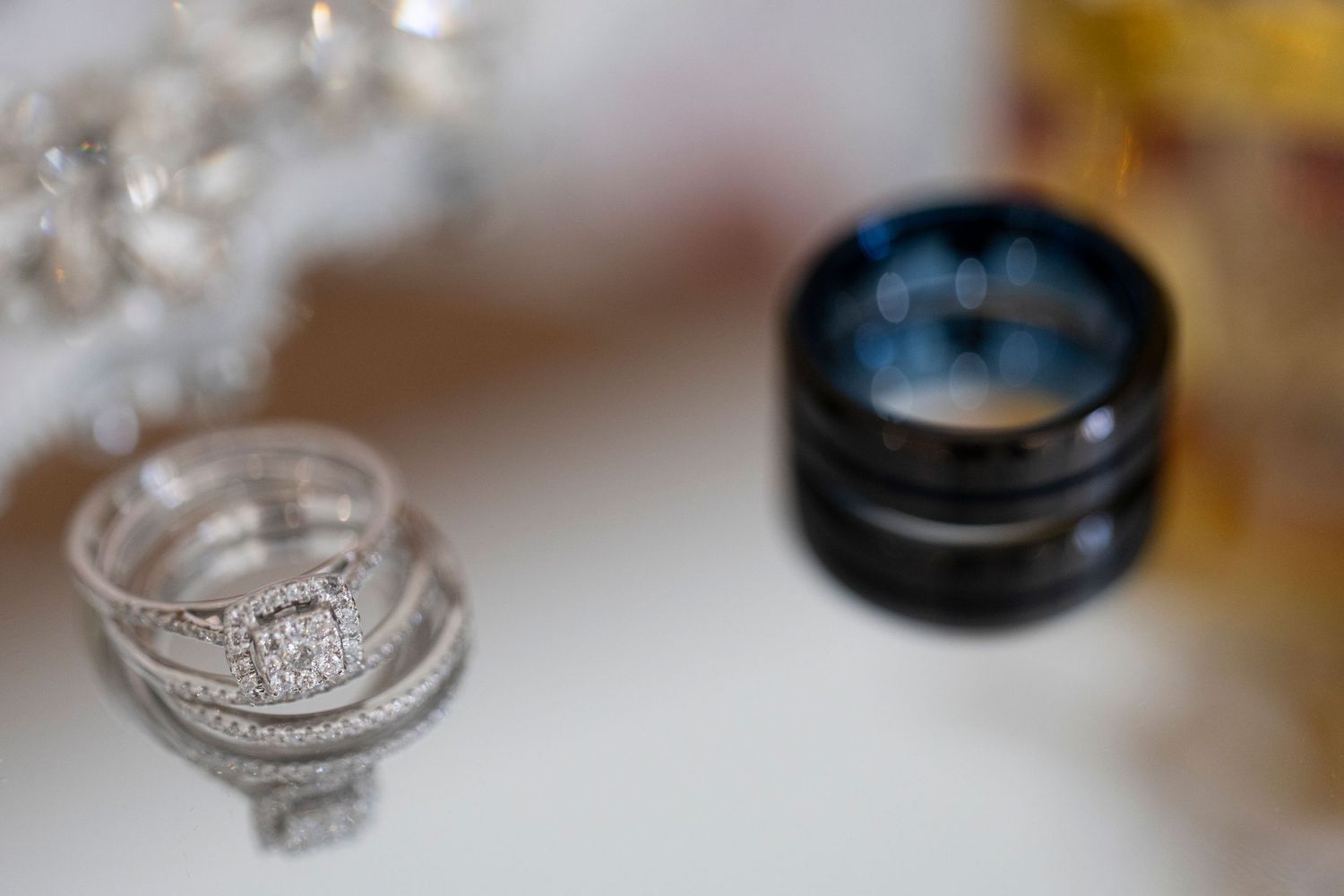 Close up of sparkling diamond engagement rings and wedding bands on a reflective surface with soft lighting.