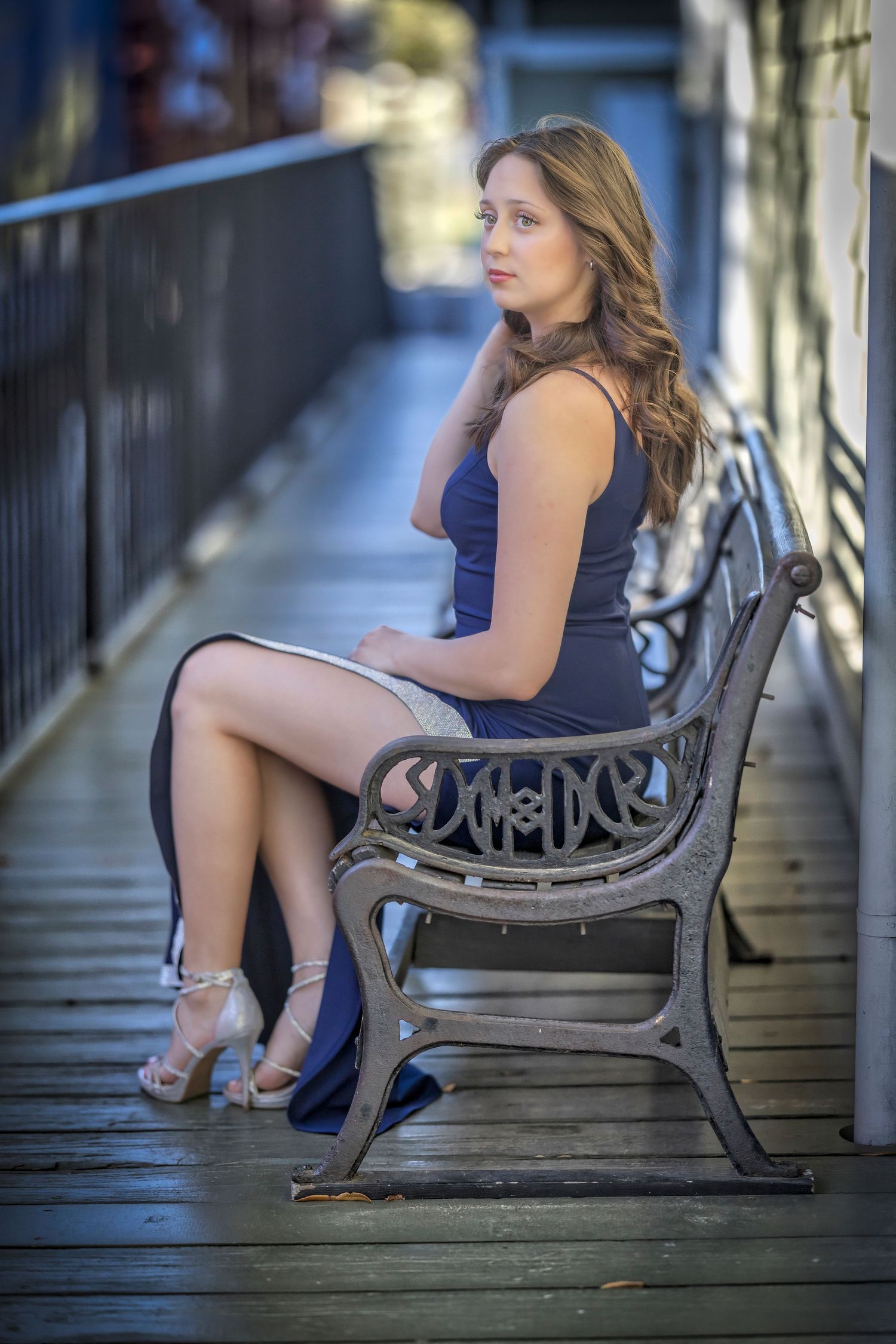 Person in a navy dress and blue heels sits on an ornate bench on a wooden deck in varying poses.