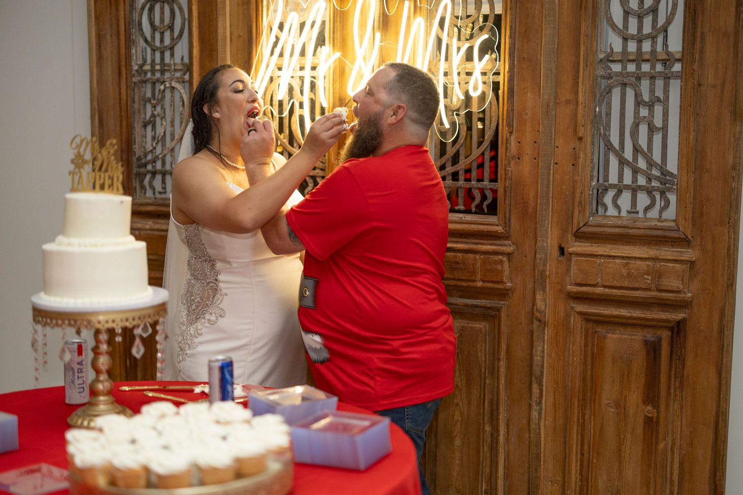 A wedding couple shares an intimate dance moment in an elegant ballroom with ornate wooden panels and chandeliers.