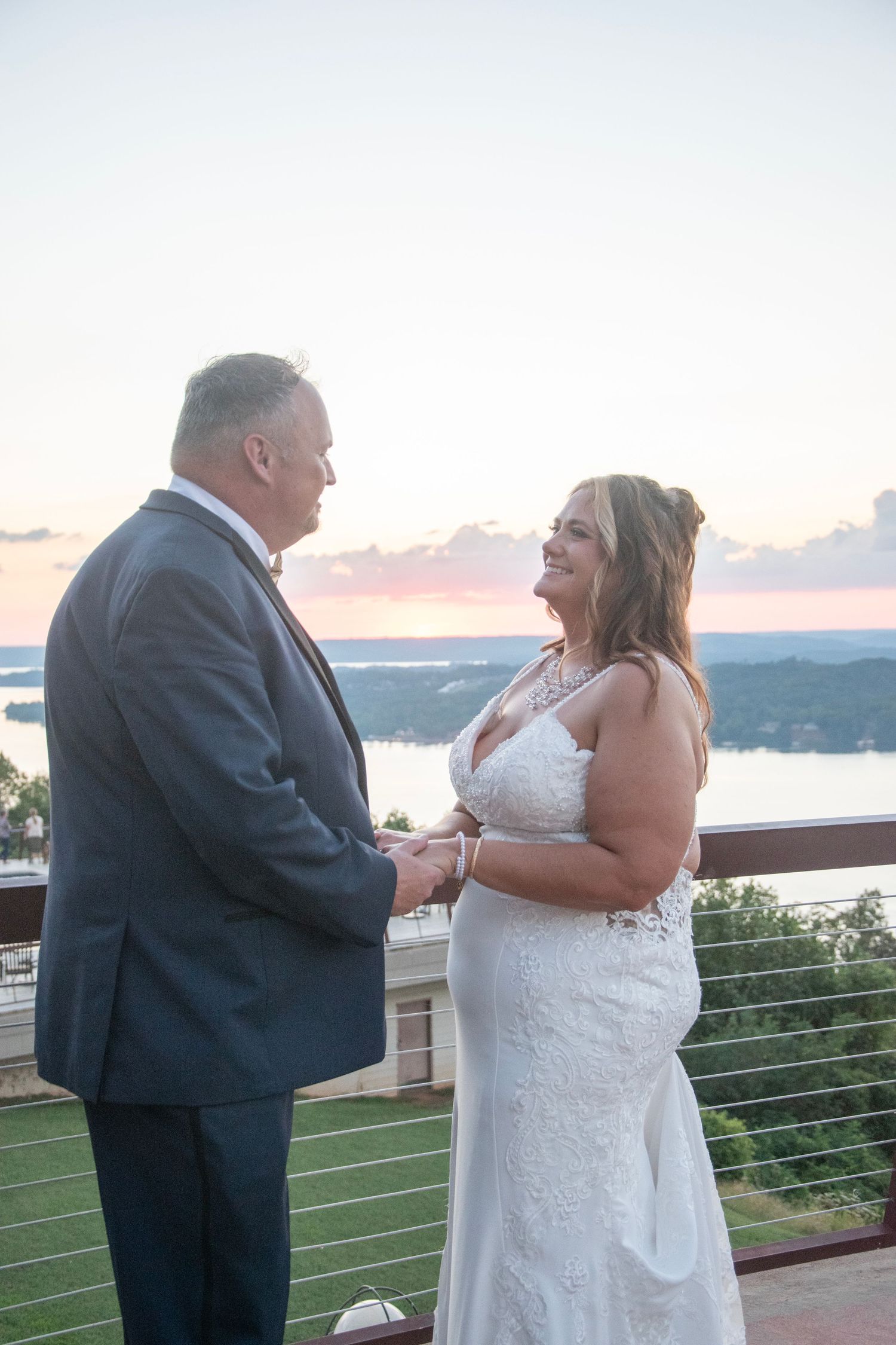 A couple shares a romantic moment during their sunset wedding ceremony overlooking a scenic mountain landscape.