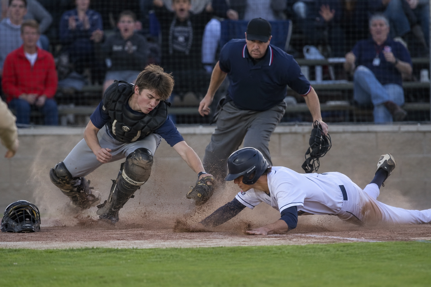 Baseball player slides into home plate as catcher attempts tag with umpire watching.