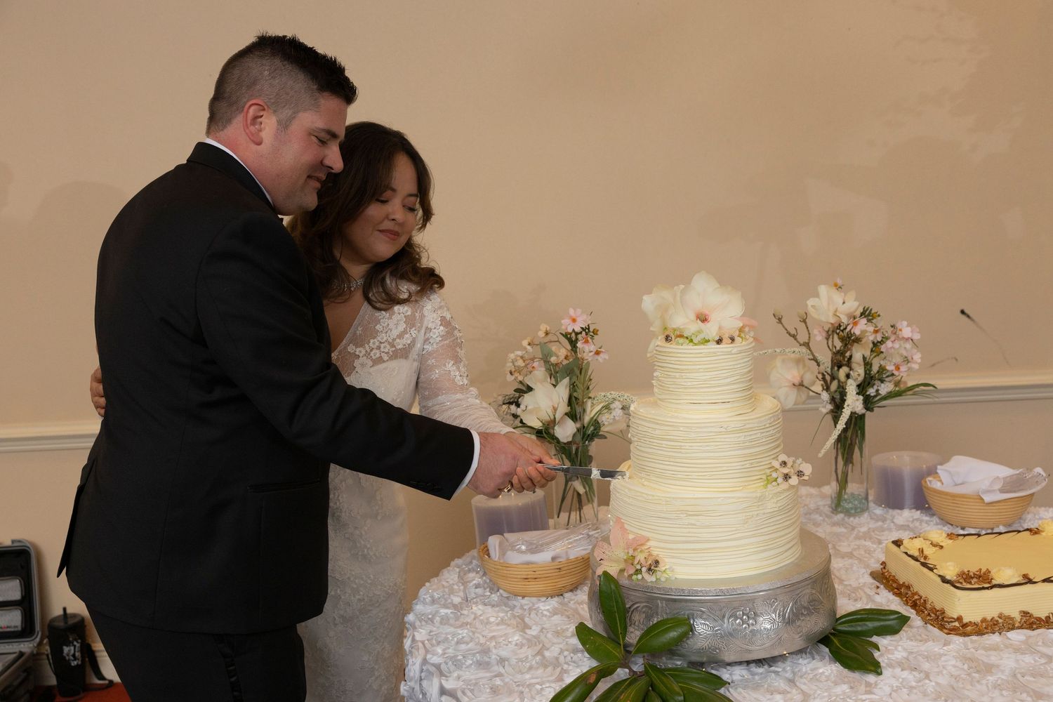 A couple cuts their white wedding cake together during their reception celebration.