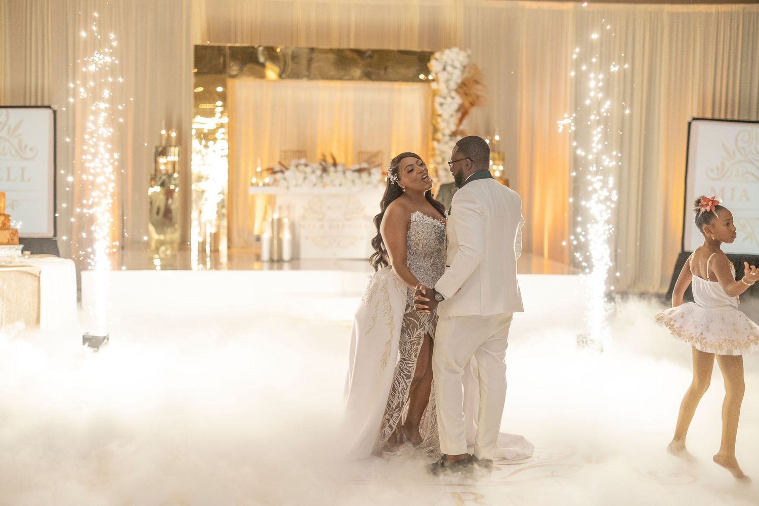 A couple shares their first dance at a wedding reception with romantic lighting and fog effects on the dance floor.