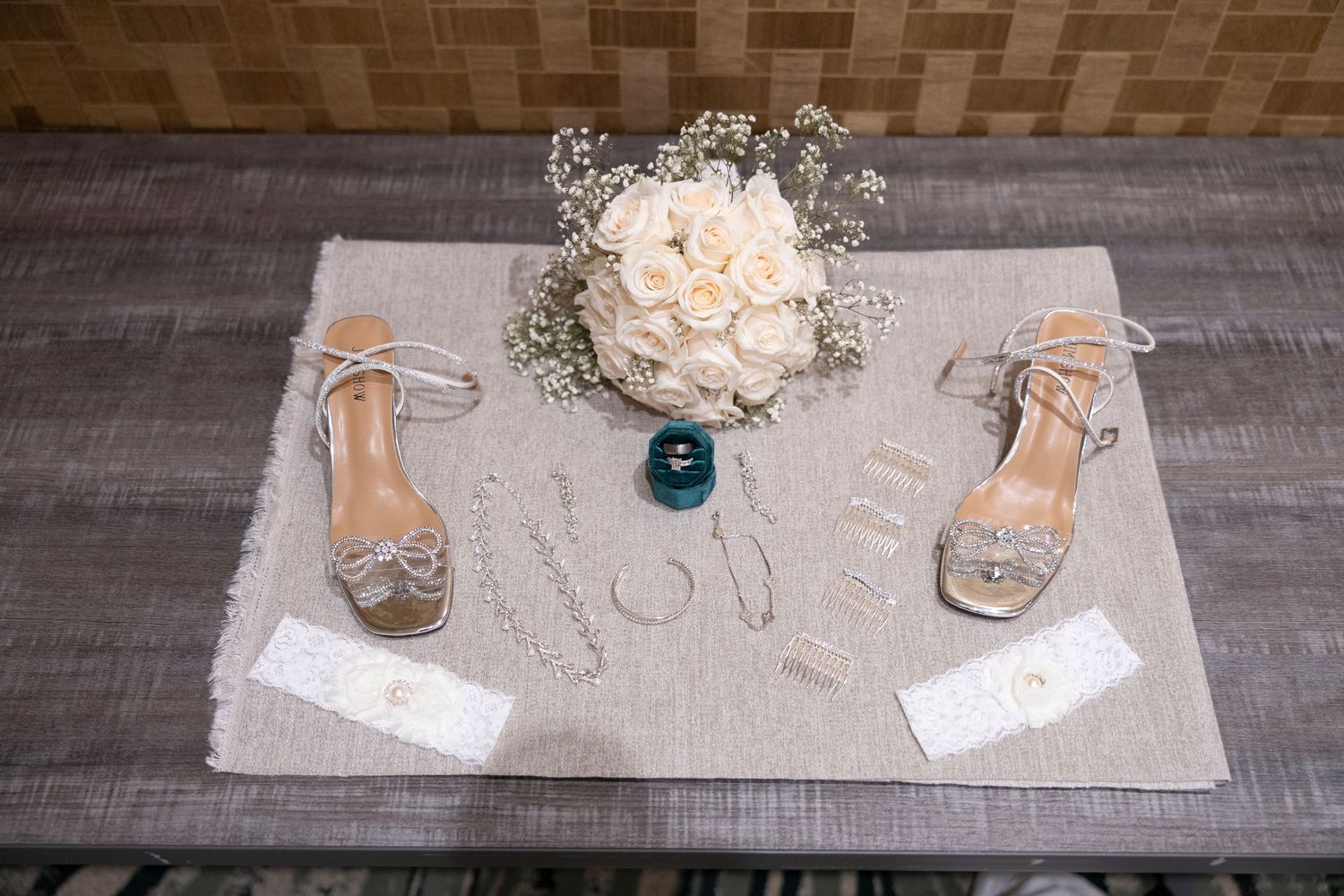 Rustic wedding details including white floral bouquets, delicate place cards, and elegant sandals arranged on wooden surfaces.
