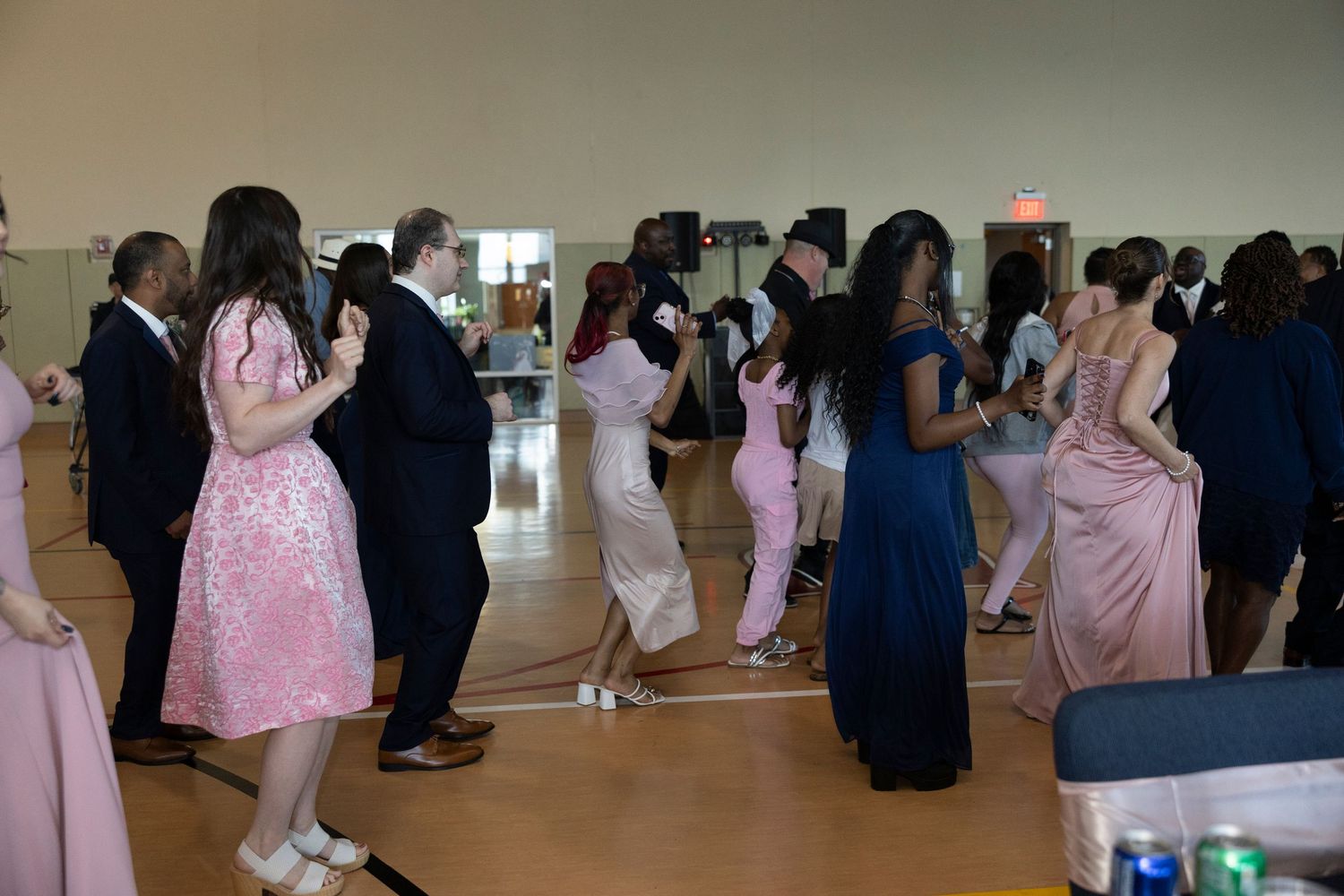Elegantly dressed guests dancing at a formal prom or gala event in a decorated ballroom venue.