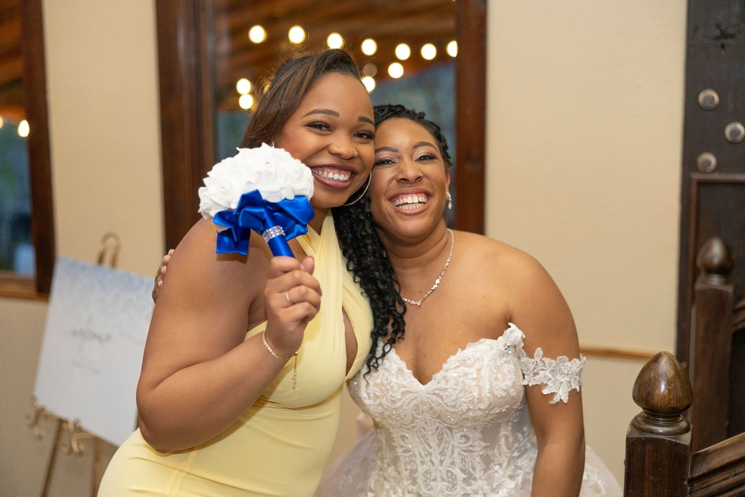 A joyful celebration scene at an indoor event with people in formal attire including a white dress and yellow dress.